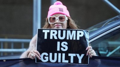 在美国大陪审团于当地时间周四起诉美国前总统特朗普后，一名反特朗普的示威者在纽约曼哈顿刑事法院外举著“特朗普有罪”的标语。（图取自路透社）