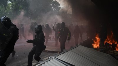 在法国巴黎的“五一”示威活动现场，防暴警察冲向在火场附近的示威者。（图取自法新社）