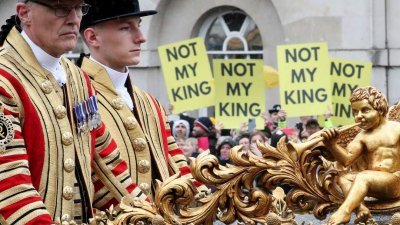 在英国国王查尔斯和王后卡米拉周六加冕后，一辆载有英国威廉王子、凯特王妃，和他们的孩子乔治王子、夏洛特公主和路易斯王子的车，从举著“不是我的君主”标语牌的抗议者身边驶过。（图取自路透社）