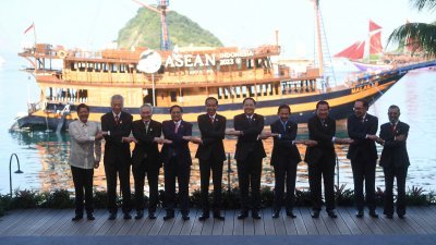 东盟成员国的领导人和代表，周三在印尼纳闽巴霍的峰会开幕时手牵手拍照，展现团结。（图取自路透社）