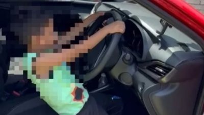 6岁男童示范他在开车时踩油门的方式。