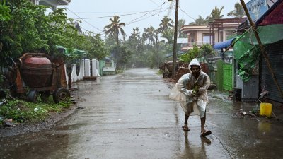 在缅甸若开邦Kyauktaw，居民在强风暴雨中前行。（图取自法新社）