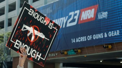 一名抗议者4月15日在美国印第安纳州印第安纳波利斯，举著写有“适可而止”的标语抗议枪支暴力。（图取自路透社）