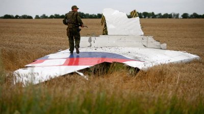 2014年7月17日，一名持枪的亲俄分裂分子站在马航MH17班机的部分客机残骸上。（图取自路透社）
