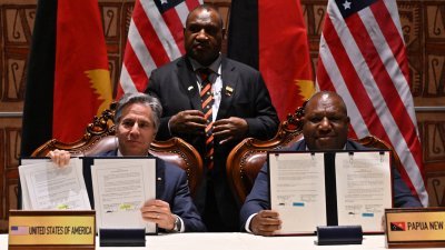在周一举行的印度-太平洋岛国合作论坛，美国国务卿布林肯（左）和巴布亚新几内亚国防部长温·巴克里·达基（右）签署一项安全协议后展示文件，巴布亚新几内亚总理马拉佩（中）见证。（图取自法新社）