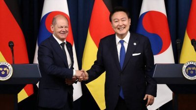 德国总理肖尔茨（左）周日，在韩国首尔总统府举行的联合新闻发布会后，与韩国总统尹锡悦握手合影。（图取自路透社）