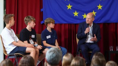 德国总理肖尔茨周一在柏林附近小镇的一所小学参加活动，与学生交流。（图取自路透社）