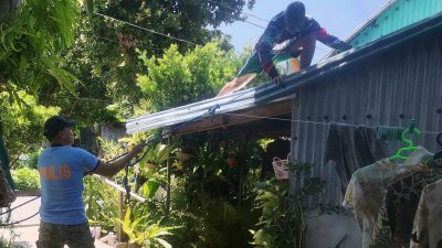 上周六，在菲律宾巴丹群岛省伊万纳镇，警察帮助居民加固房屋的屋顶，以准备预防台风“玛娃”的侵袭。（图取自法新社）