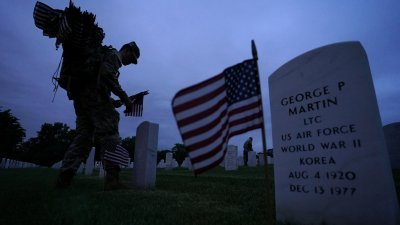 美国第3步兵团士兵本月25日，为纪念阵亡将士纪念日，在26万座坟墓前放置美国国旗。（图取自路透社）