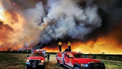 在加拿大不列颠哥伦比亚省圣约翰堡附近的一场野火中，消防员本月14日站在坎卢普斯消防救援货车上。（图取自坎卢普斯消防救援/路透社）