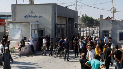 民众周五在拉法边境加沙一侧，等待自10月7日冲突爆发以来滞留在以色列和约旦河西岸的巴勒斯坦工人。（图取自路透社）