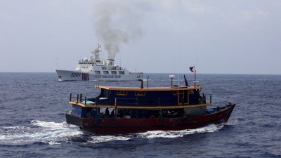 一艘中国海警船（后）10月4日在南中国海驶近一艘菲律宾补给船。（路透社档案照）