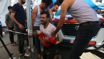 以色列军队不分昼夜轰炸加沙城，一名男子当地时间周六急忙抱着一名受伤的幼儿前往希法医院。（图取自法新社）