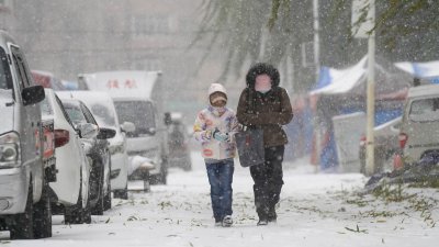 中国黑龙江省哈尔滨市气象台周日晚上分发布暴雪红色预警信号，图为周一，市民冒雪出行。（图取自中新社）