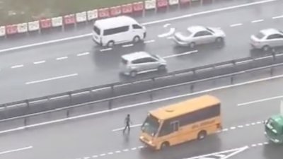 男子横穿高速公路，再迎面走向行驶而来的巴士。