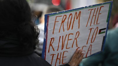 德国柏林一名示威者当地时间周六在声援巴勒斯坦人的集会上，展示写有亲巴勒斯坦口号“从河流到大海”的标语牌。（图取自法新社）