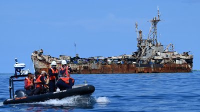 菲律宾海岸警卫队人员和记者，上周五（10日）乘坐小型充气艇，前往“马德雷山”号废弃军舰执行补给任务。（图取自法新社）