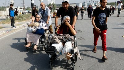 在以色列袭击中受伤并住在希法医院的巴勒斯坦伤患妇女，上周五在亲友的帮助下向加沙南部撤离。（图取自路透社）