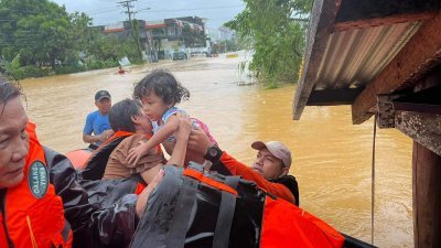 菲律宾海岸警卫队周三发布的照片显示，海岸警卫队人员周二在菲律宾中部北萨马岛卡塔曼镇的一个村庄，从一间被洪水淹的屋子救出一名儿童。（图取自菲律宾海岸警卫队法新社）