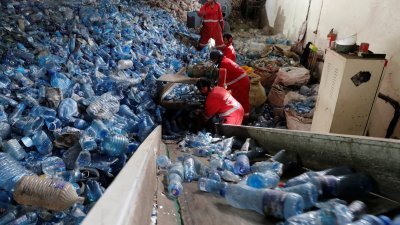 肯尼亚内罗毕工业区一家塑料碎片出口公司的工厂内，工人将透明塑料瓶装入破碎机。（图取自路透社）