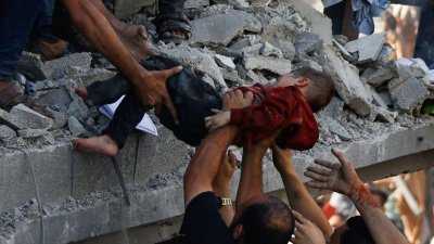加沙一所房子被空袭倒塌，巴勒斯坦人协力拯救一名受伤的孩子。（图取自路透社）