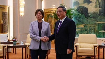 法国外交部长科隆纳（左）和中国总理李强，周五在中国北京人民大会堂会面时握手合影留念。（图取自路透社）