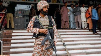 巴基斯坦准军事士兵在周六发生火灾的商场外驻守。（图取自路透社）