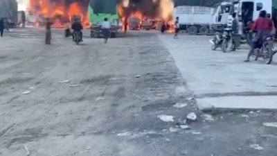 11月23日发布在社交媒体的视频截图显示，在缅甸木姐附近的中缅边境附近，一队货车燃烧，烟雾升腾。（图取自路透社）