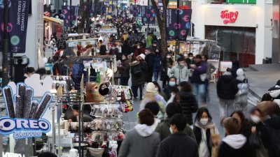 韩国首尔明洞购物区，街头小贩（左）等待顾客。（图取自路透社档案照）