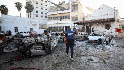 加沙的阿赫利阿拉伯医院10月17日发生爆发造成数百人死亡，一名媒体人员在隔天走在医院附近。（图取自路透社）
