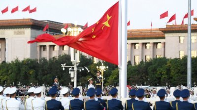 中国北京天安门广场星期天清晨举行国庆升旗仪式，升旗手扬起五星红旗，国旗徐徐升起。（图：星岛网）
