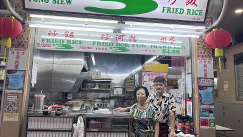 马松胡（右）与妻子在白桥巴刹熟食中心卖3新元炒饭和炒河粉。