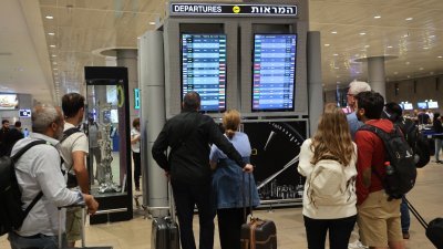 受到以巴再度爆发冲突影响，许多航空公司取消前往以色列班机，以色列特拉维夫附近的本古里安机场，乘客们看著航班信息牌，关注航班动态。(图取自法新社)