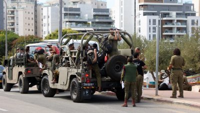 以色列陆军预备役人员周六搭乘军车前往特拉维夫南部的军事基地。（图取自法新社）