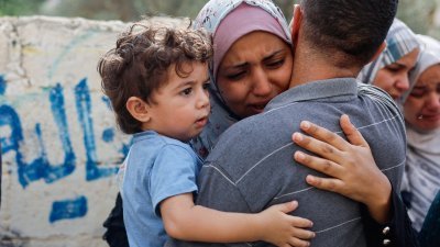 一位巴勒斯坦女性周一在加沙举行的一场葬礼上，抱著她的家人哭泣，而男童似乎不明白周围所发生的事情。（图取自路透社）