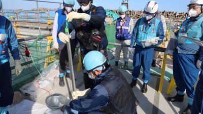 东京电力公司官员从福岛第一核电厂的上游蓄水池，取样进行检测。（图取自东电/法新社）