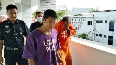 身穿橙色扣留服的被告被庭警押往法庭时用衣服遮脸。