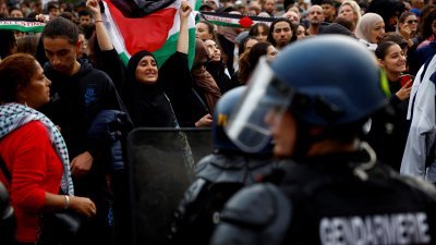 周四在巴黎共和广场，法国宪兵包围示威民众，有的高举挥舞巴勒斯坦国旗，有的吹口哨与鼓掌，并用法语高喊“我们都是巴勒斯坦人”等口号。（图取自路透社）