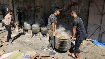 在加沙南部城市汗尤尼斯，安置大批巴勒斯坦难民的联合国设施，人们周日在燃料和天然气短缺的情况下用柴火做饭。（图取自法新社）