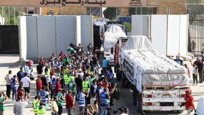 停在埃及边境多时的人道援助卡车，周六陆续通过拉法关卡前往加沙地带，埃及的志愿者在关卡附近聚集庆祝。（图取自路透社）