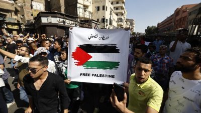 在埃及首都开罗，支持巴勒斯坦的民众在上周五的中午祈祷结束后举行抗议活动，举起画有巴勒斯坦旗的横幅。（图取自法新社）