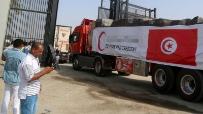 在埃及一则的拉法口岸，人们看著第2批载著援助物资的货车车队在周日进入加沙地带。（图取自法新社）