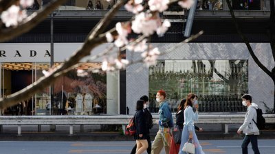 新冠肺炎疫情期间，戴著口罩的民众在日本东京走过斑马线。（图取自路透社）