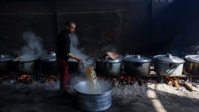 在加沙地带拉法的联合国庇护所，由于燃料缺乏，住在那的巴勒斯坦人用柴火准备食物。（图取自法新社）