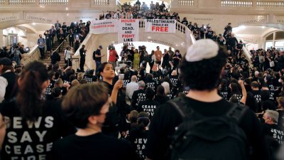 身穿印有口号黑衣的示威者，周五在美国纽约市的中央车站抗议，促以色列和哈马斯停火。（图取自法新社）