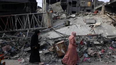 自从周五傍晚开始，加沙的通讯网络瘫痪，几乎完全与外界隔绝。图为在加沙地带南部与埃及交界的拉法城镇，妇女们走过被以色列轰炸后毁损的建筑。（图取自法新社）