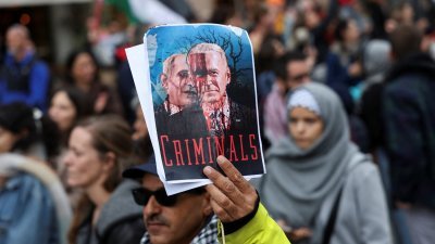 在西班牙马德里。示威者在周日上街声援加沙地带巴勒斯坦人，一名示威者举著一张海报，海报上描绘了美国总统拜登和以色列总理内塔尼亚胡浑身是血，并写上“犯罪分子”。（图取自路透社）