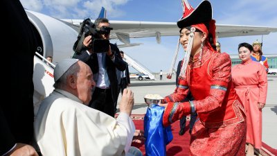 罗马天主教教宗方济各抵达乌兰巴托的机场后，一名身穿蒙古传统服装的女子向他递上奶干，一种蒙古小吃。（图取自梵蒂冈媒体/路透社）