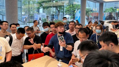 在中国广东省深圳市华为旗舰店内，一名工作人员8月30日向顾客介绍新款华为 Mate 60智能手机。（图取自路透社）
