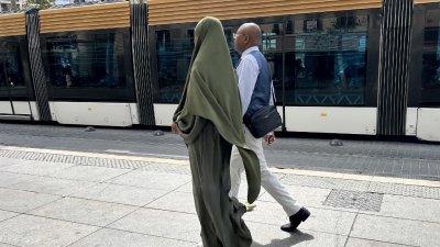 一名身穿Abaya长袍的穆斯林女子（左）8月29日走在法国南部马赛的街道上。（图取自法新社）